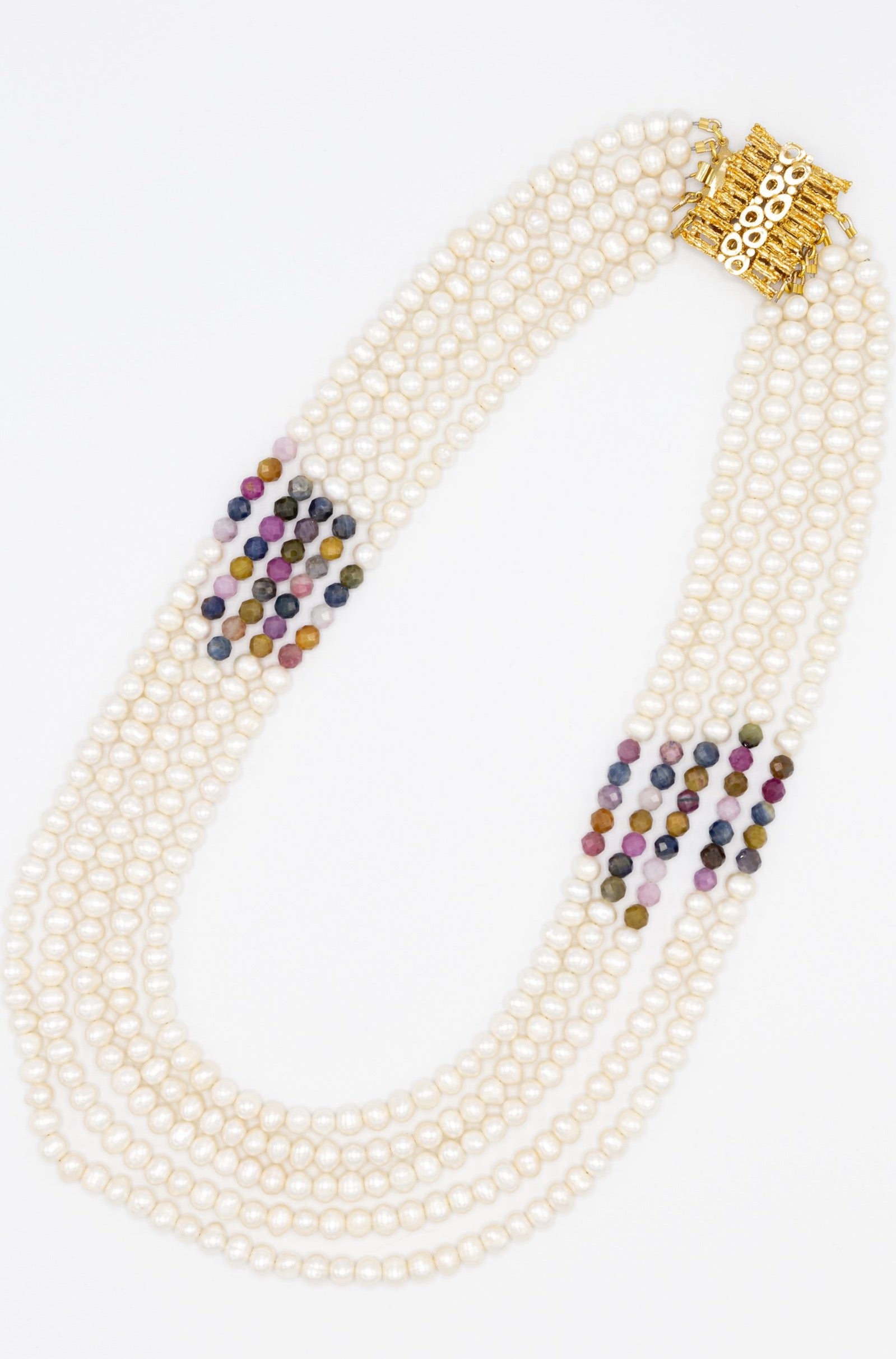 Inspired by traditional carpentry, this outstanding necklace features five rows of carefully curated freshwater pearls and multicolour rubies. Finished with eye- catching gold plated silver clasp