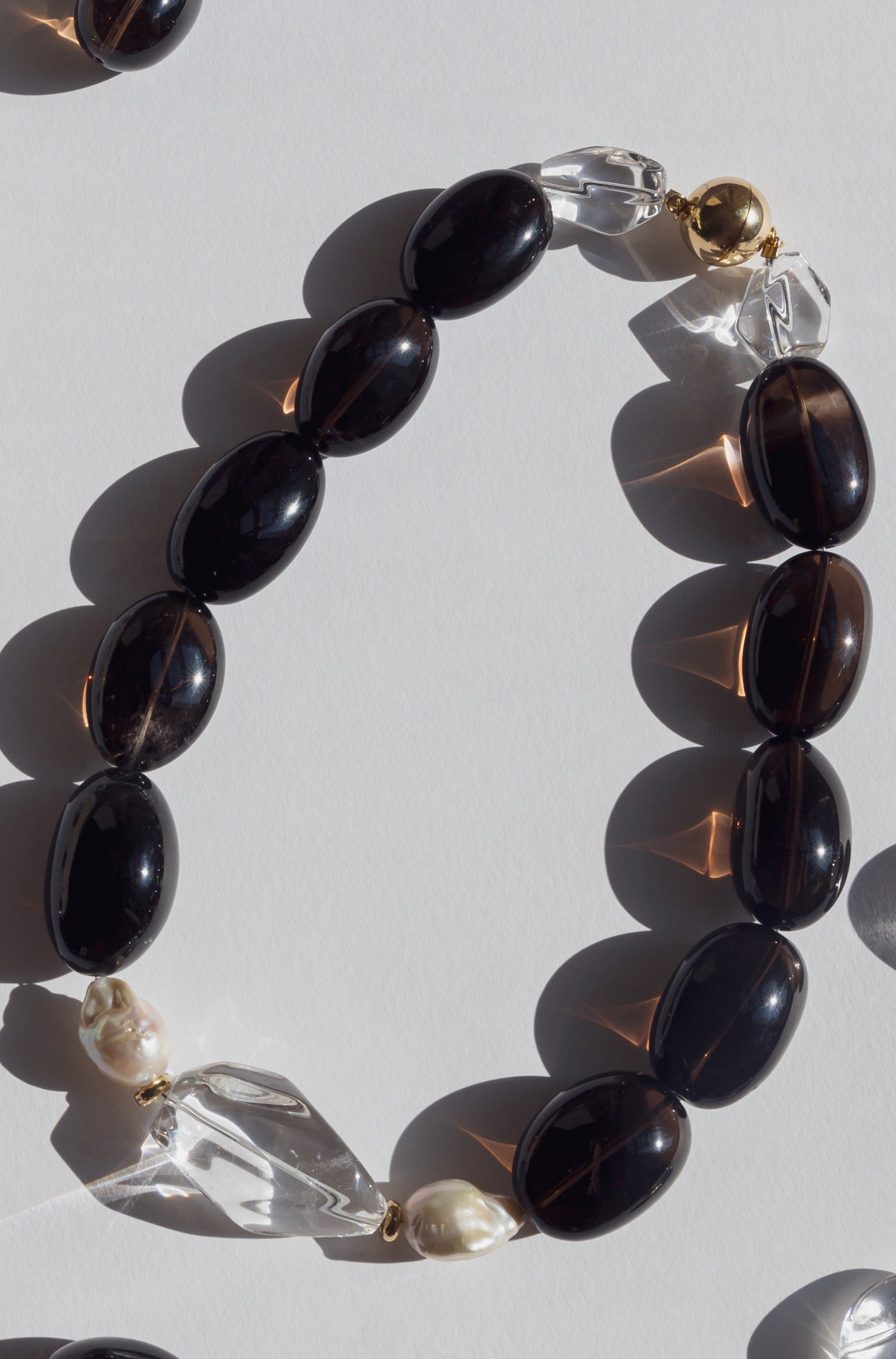 Always elegant and exquisite dark smokey quartz and white colour combination adds to every style. Smokey and crystal clear quartz, accompanied with baroque pearls, gold plated silver round beads and magnetic clasp